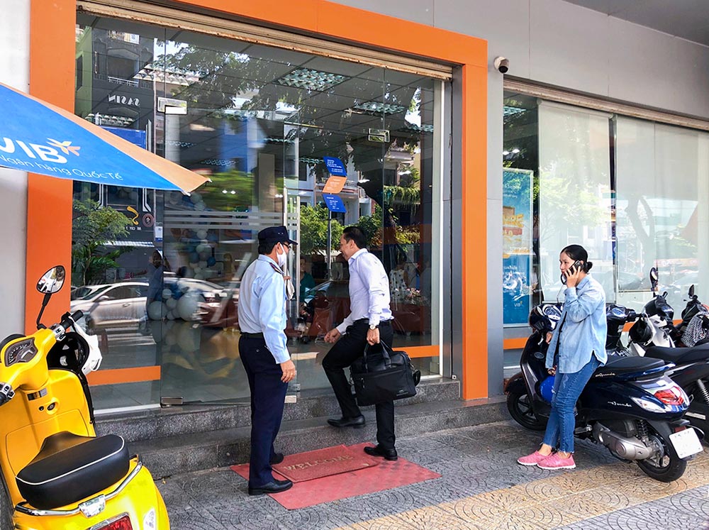 Nhân viên bảo vệ ngân hàng hỗ trợ mở cửa cho khách tới giao dịch nhan-vien-bao-ve-ngan-hang-ho-tro-mo-cua-cho-khach